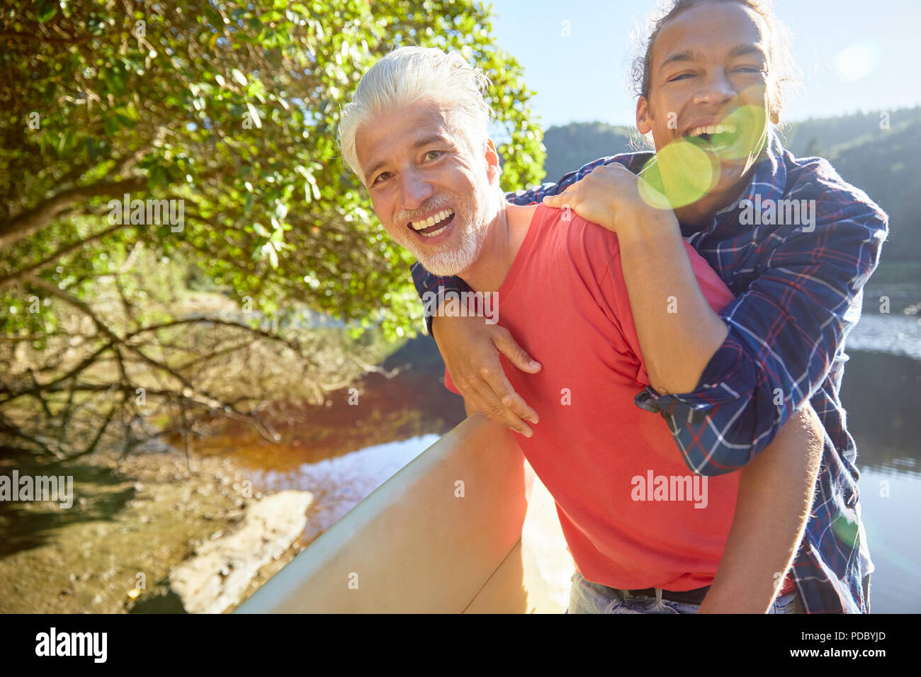Portrait playful father and son at sunny summer lake Stock Photo