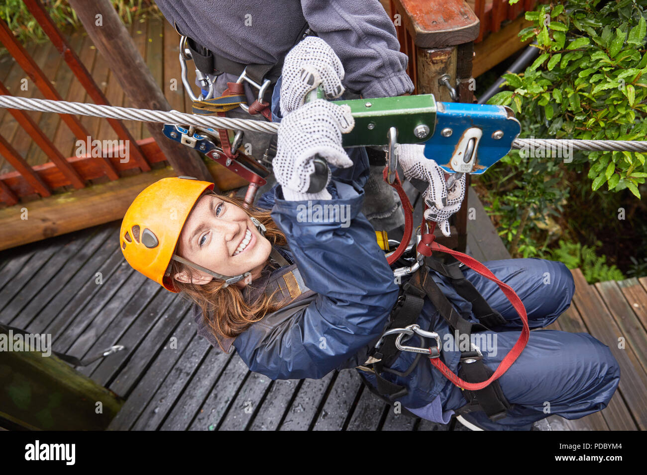 Portrait smiling young woman zip lining Stock Photo