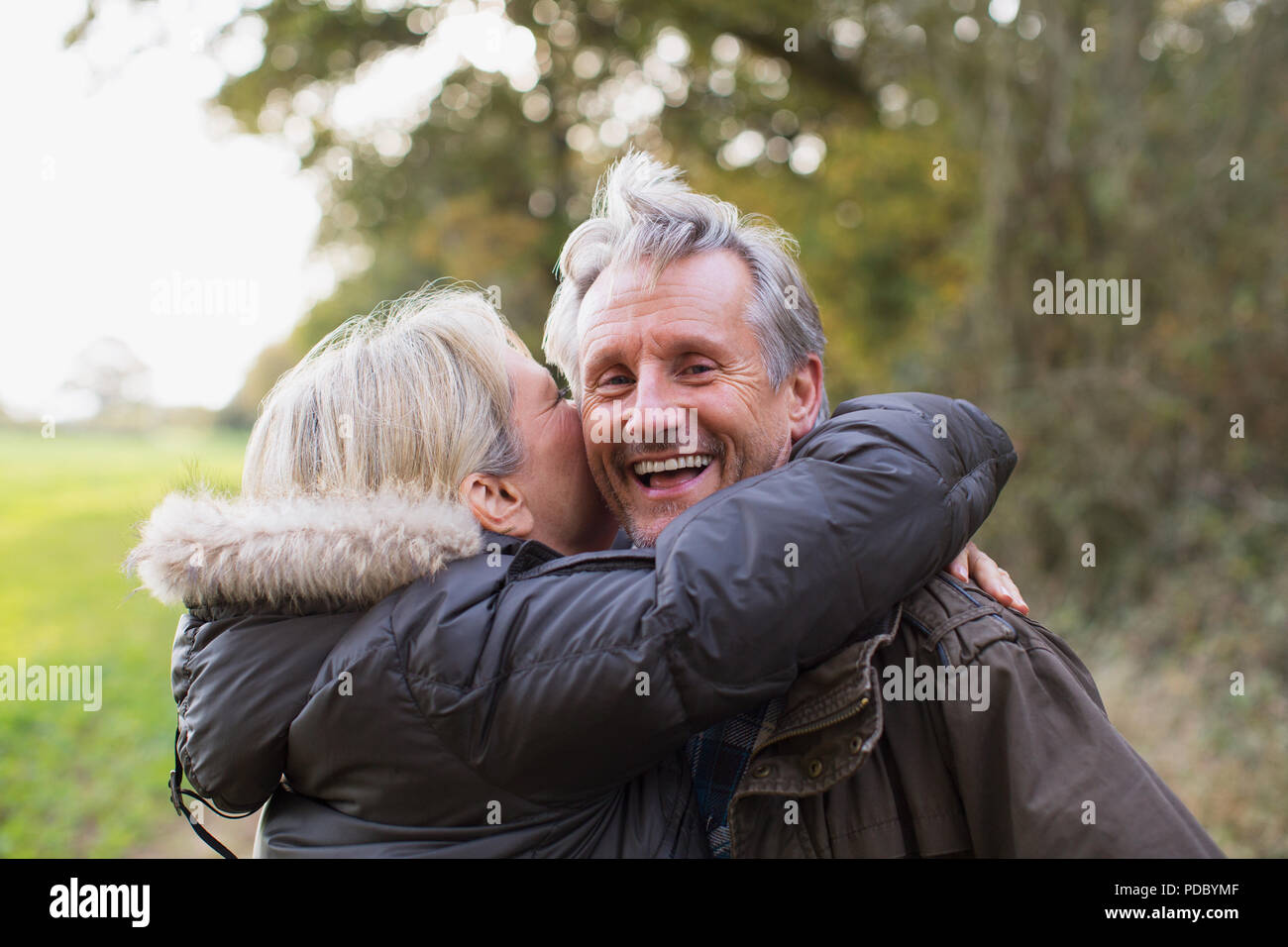 Portrait happy, playful mature couple hugging in park Stock Photo