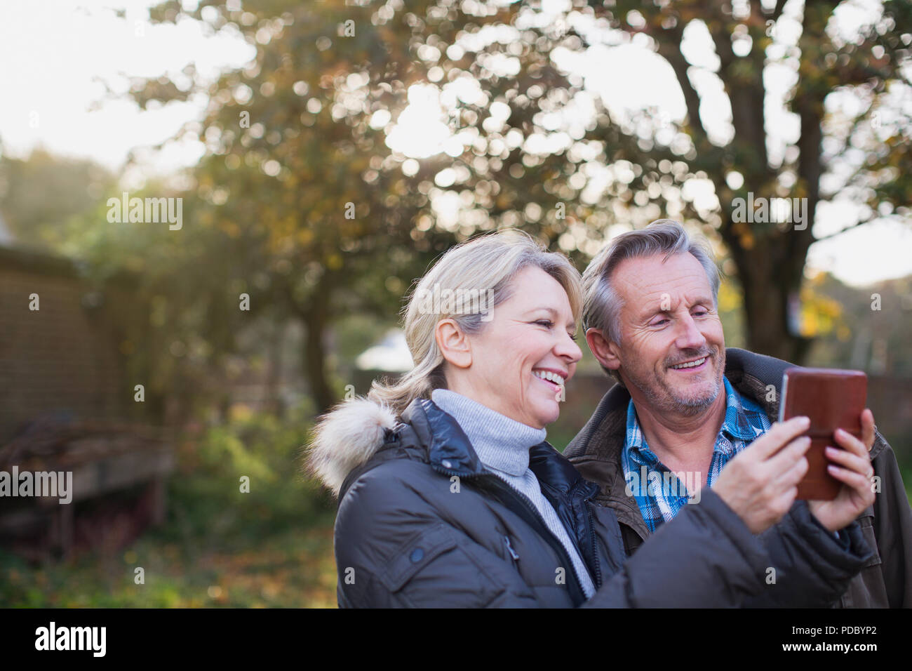 Mature couple using smart phone in autumn backyard Stock Photo