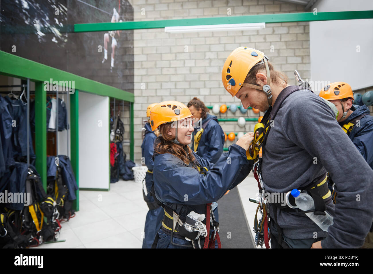 Woman helping man with zip line equipment Stock Photo