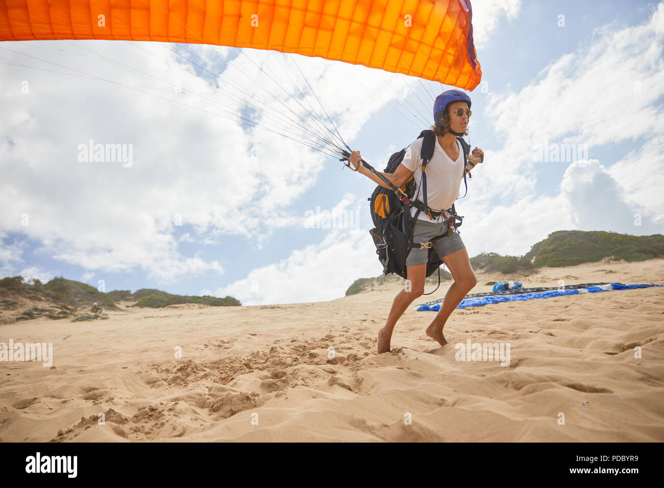 Male paraglider running with parachute on beach Stock Photo