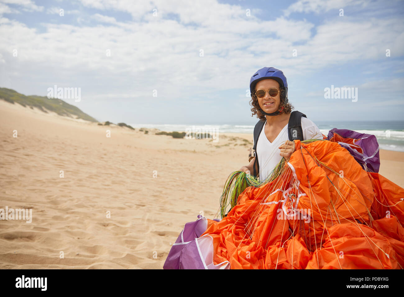 Portrait smiling male paraglider with parachute on beach Stock Photo
