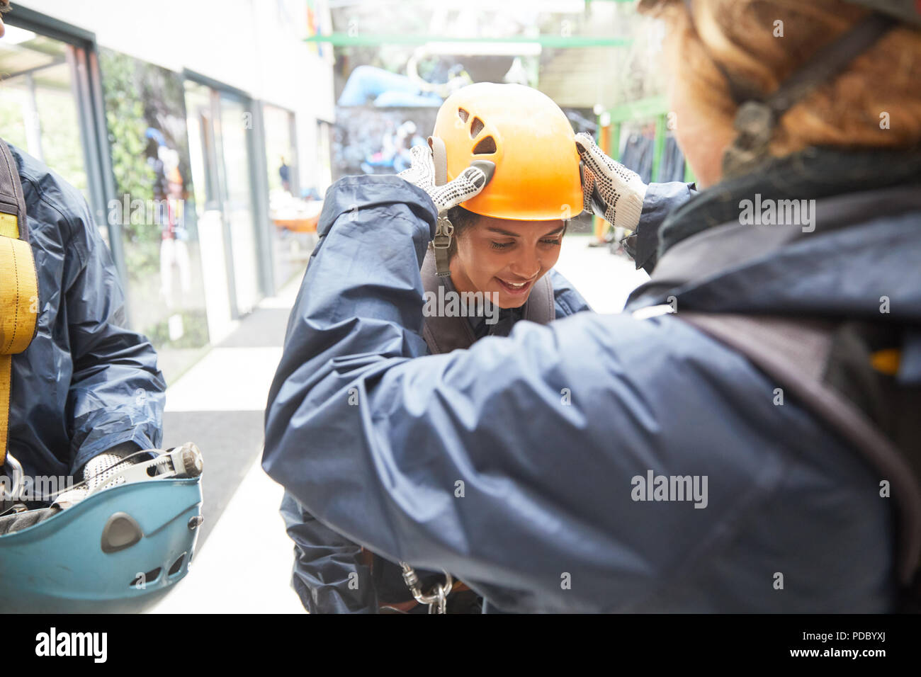 Woman helping friend with zip line helmet Stock Photo