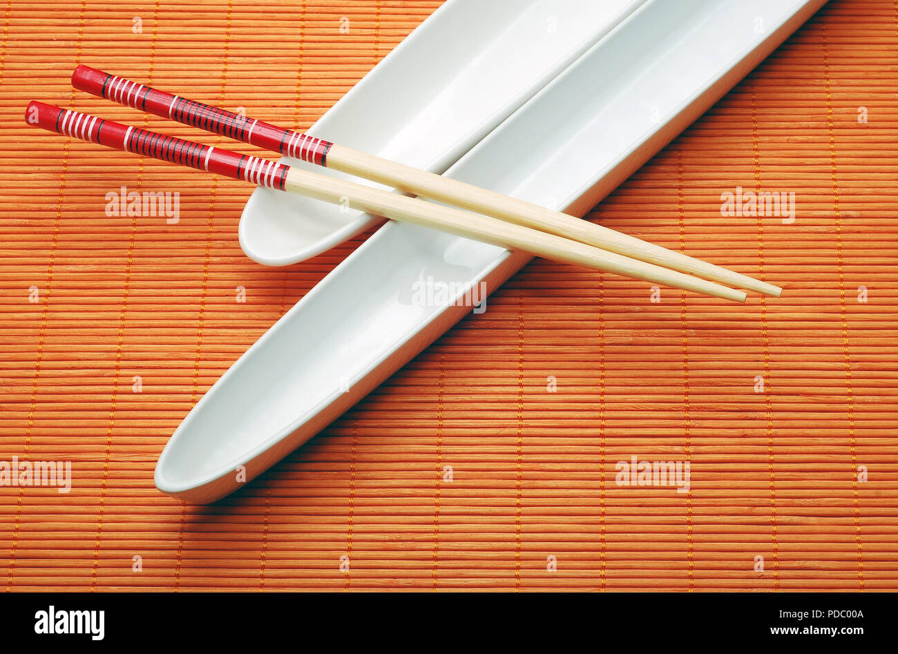 chopsticks over orange bamboo mat, asian culture Stock Photo