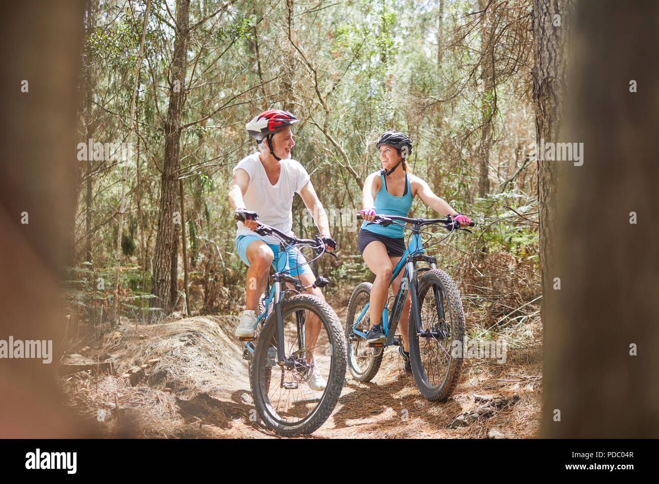 Father and daughter mountain biking on trail in woods Stock Photo