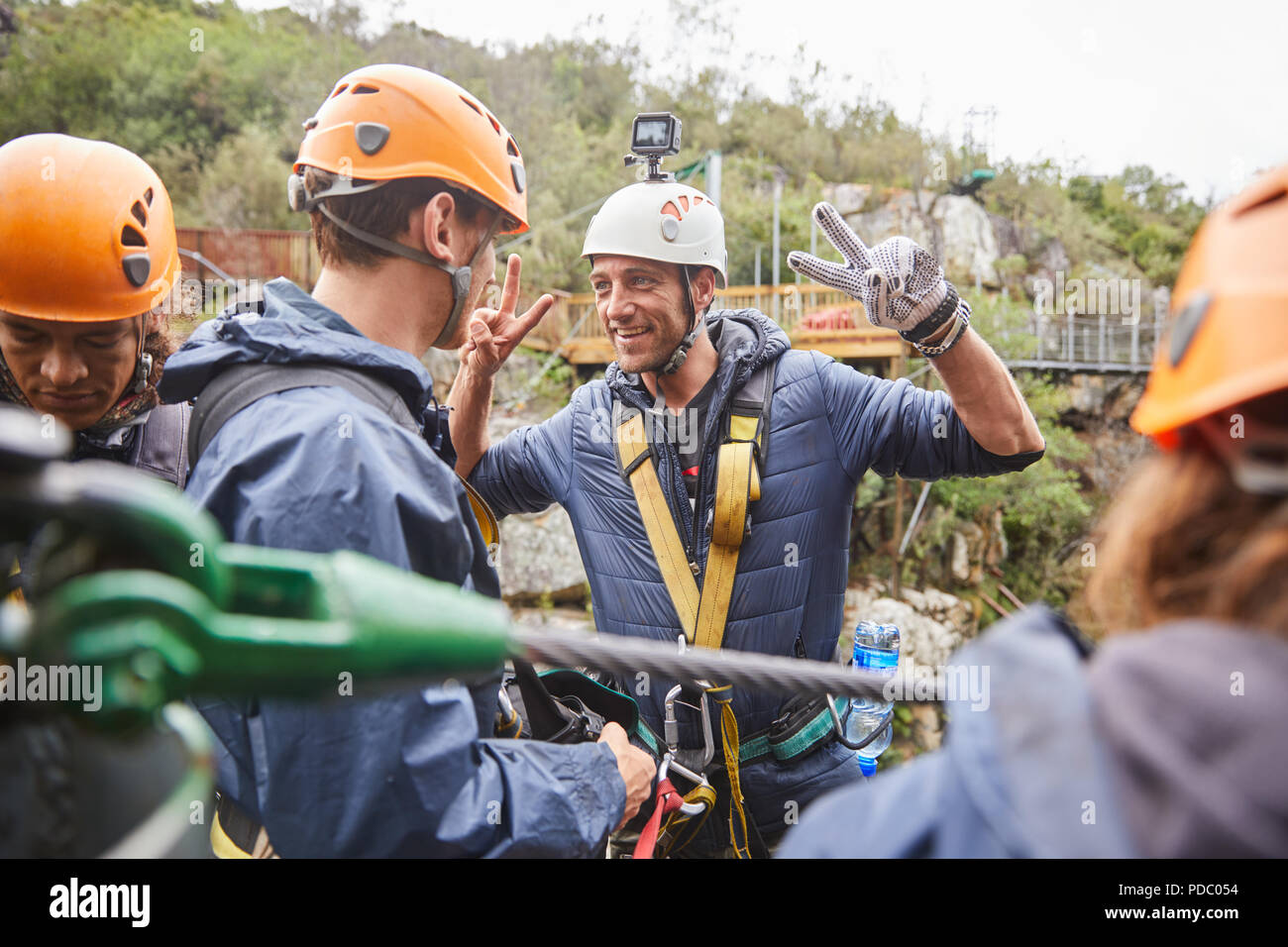 Enthusiastic man preparing to zip line, gesturing peace sign Stock Photo