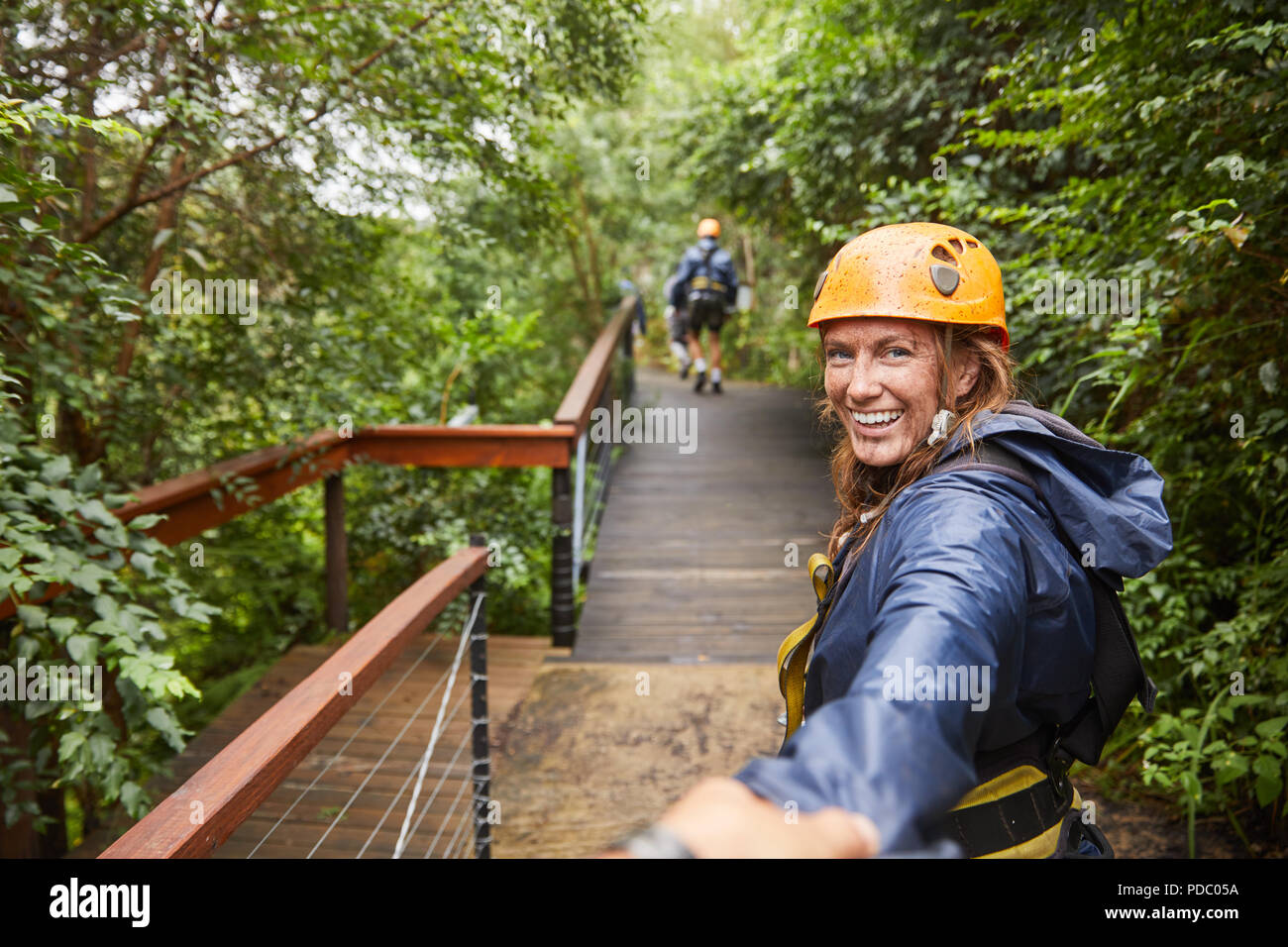 Portrait smiling woman zip lining in woods Stock Photo