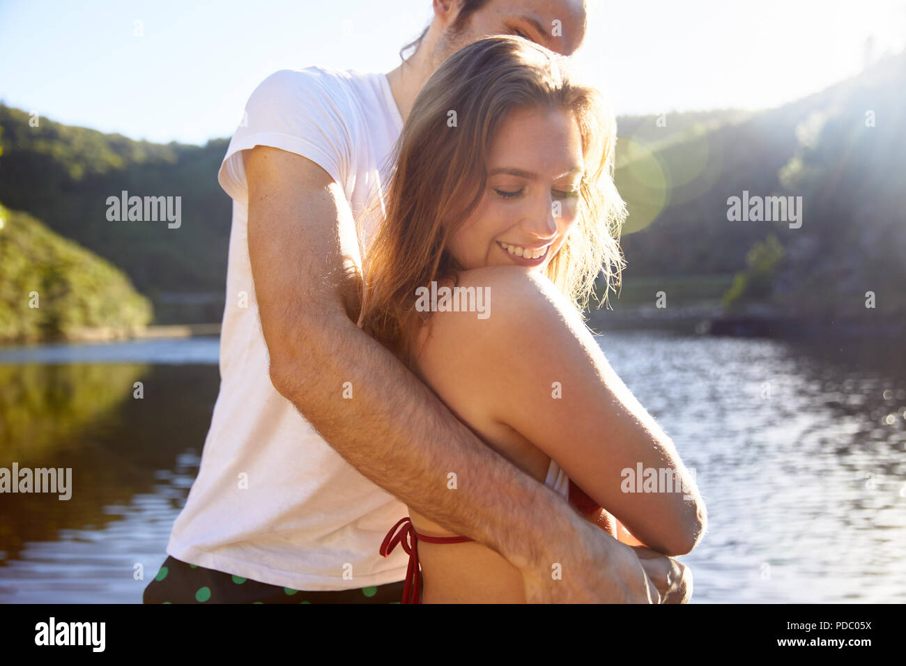 Affectionate couple hugging at sunny summer lake Stock Photo