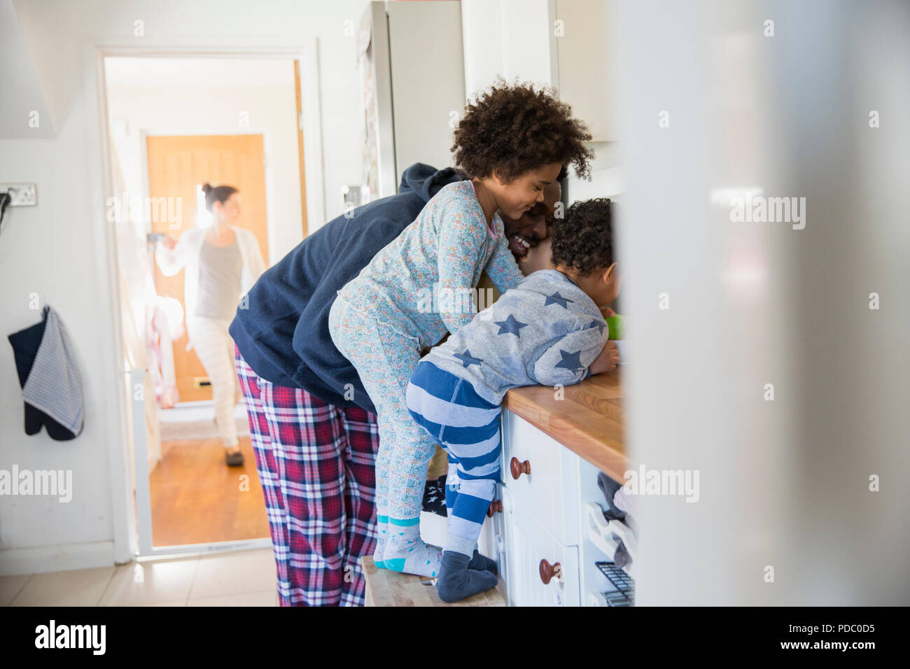 Father and children in pajamas at kitchen counter Stock Photo