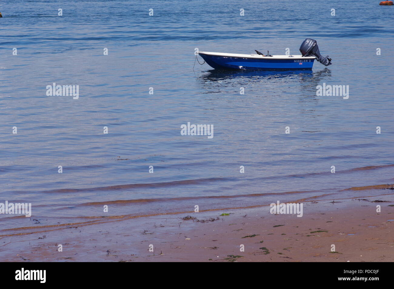 Small Blue Dinghy Boat with Outboard Engine Moored on the Calm Waters