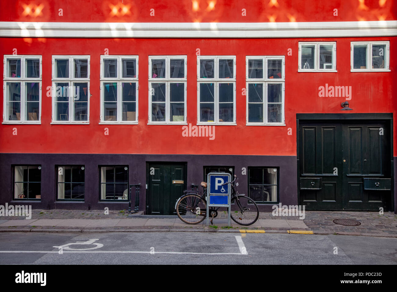parking sign and parked bicycle near red building on street in
