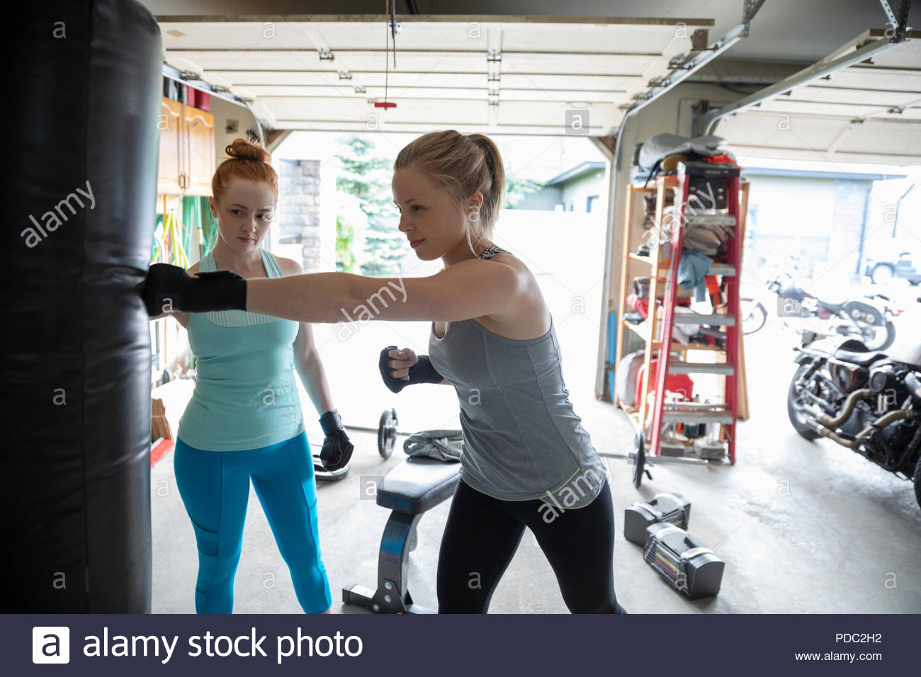 Young women friends boxing at punching bag in garage Stock Photo Alamy