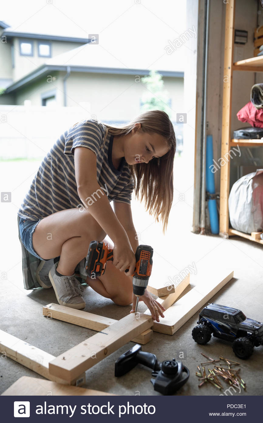 Tween girl building remote controlled car ramp with power drill in garage Stock Photo