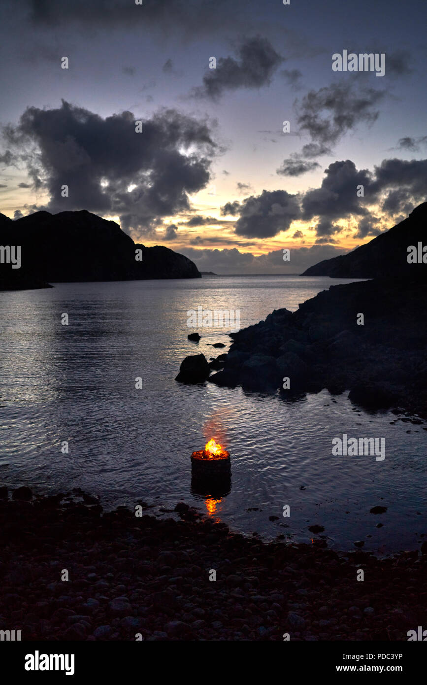 Firestack by Artist Julie Brook.West coast of The Isle of Lewis. Scotland. Elemental sculpture of hollow stone cairn with fire lit on an incoming tide Stock Photo