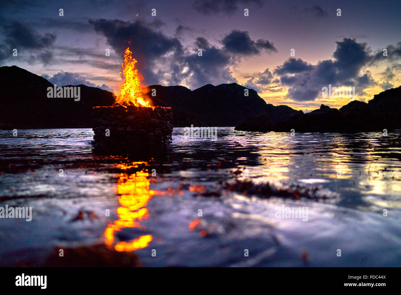 Firestack by Artist Julie Brook.West coast of The Isle of Lewis. Scotland. Elemental sculpture of hollow stone cairn with fire lit on an incoming tide Stock Photo