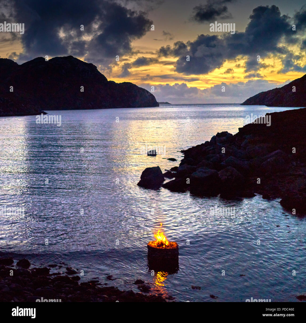 Firestack by Artist Julie Brook.West coast of The Isle of Lewis. Scotland. Elemental sculpture of hollow stone cairn with fire lit on an incoming tide Stock Photo