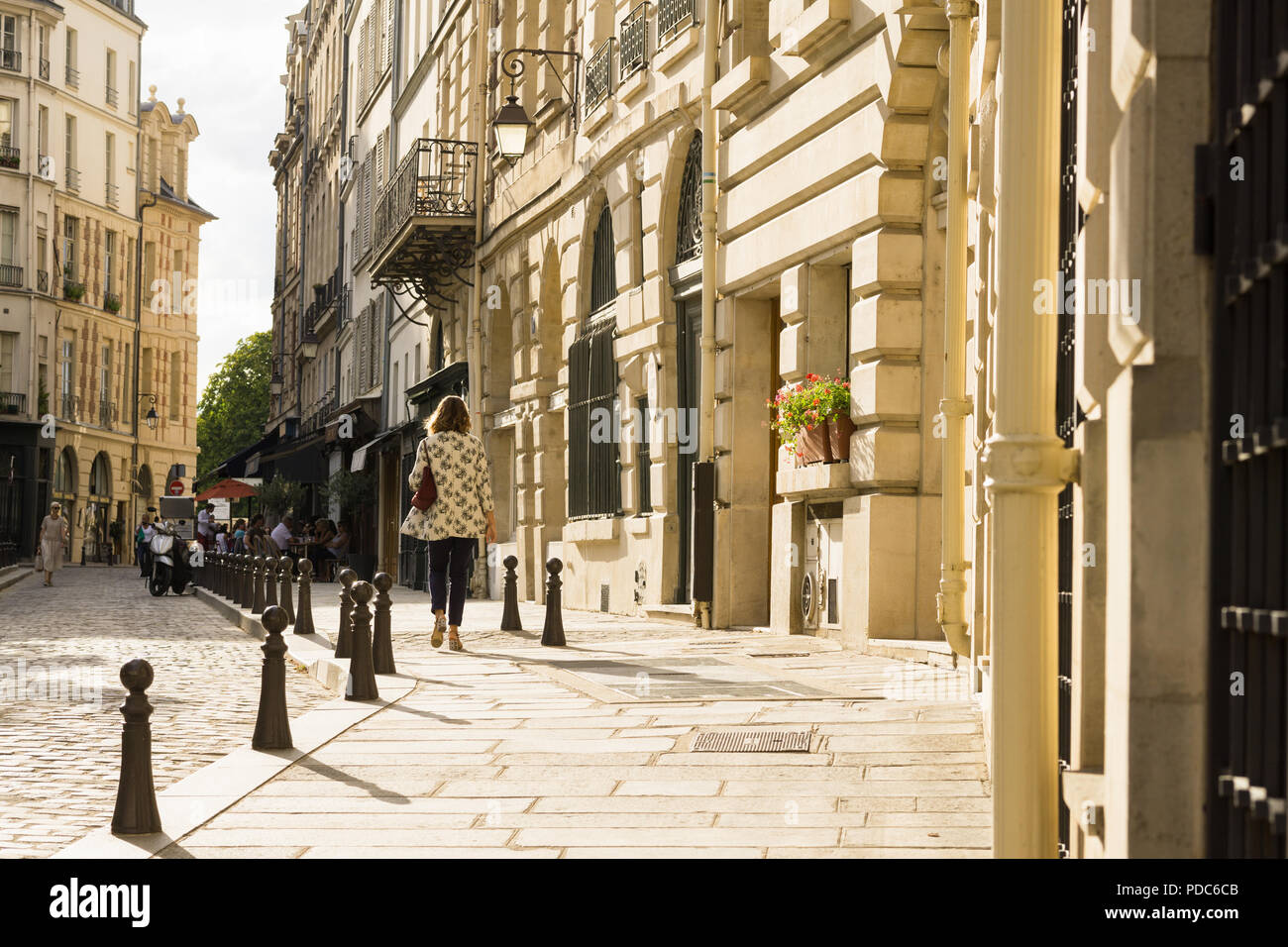 Paris street scene - a woman walking along the Place Dauphine on the Ile de la Cite in Paris in late afternoon, France, Europe. Stock Photo