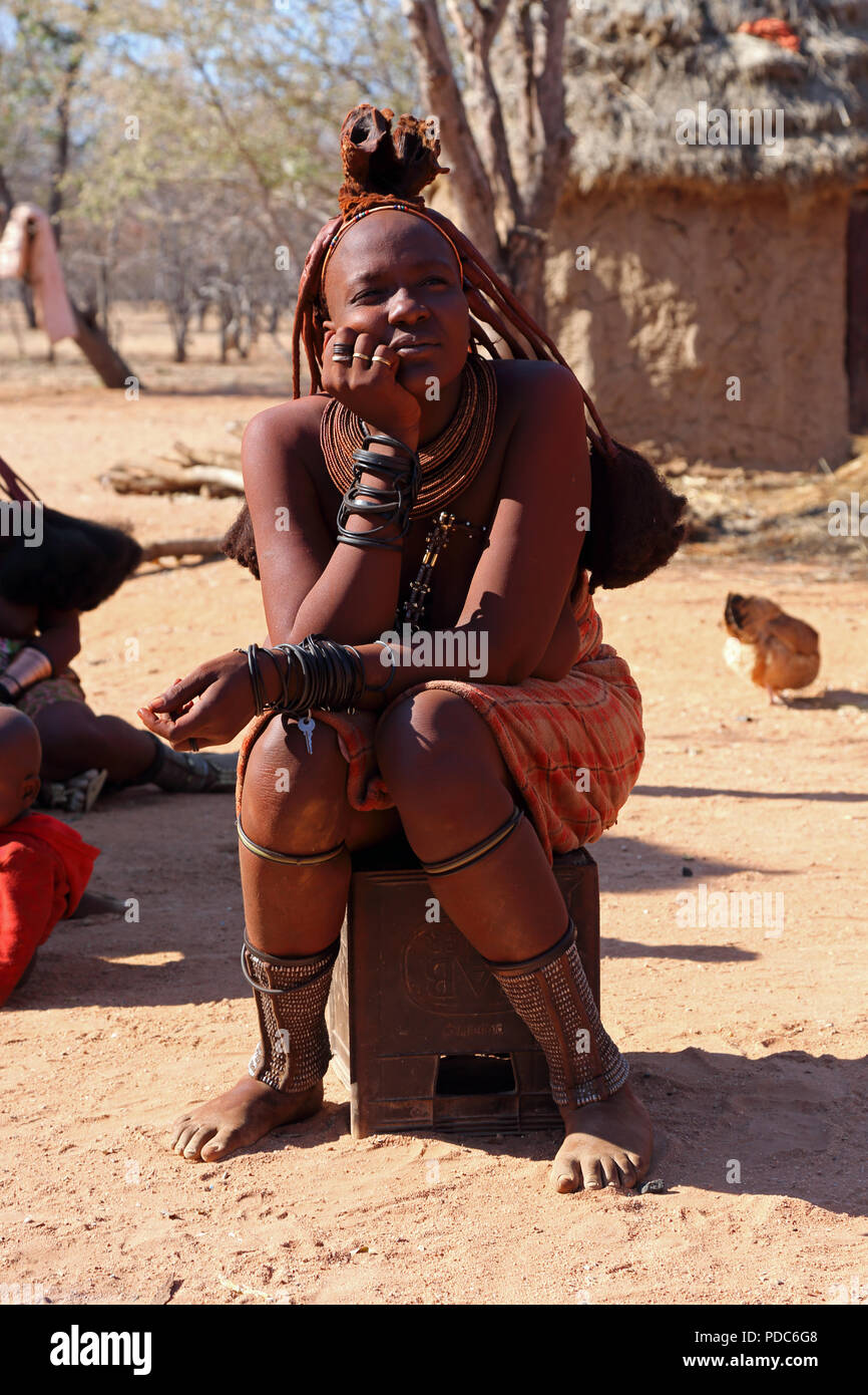 Himba woman, Otjikandero village, northern Namibia. Red ochre paste is used to cleanse the skin and help protect against mosquito bites.. Stock Photo
