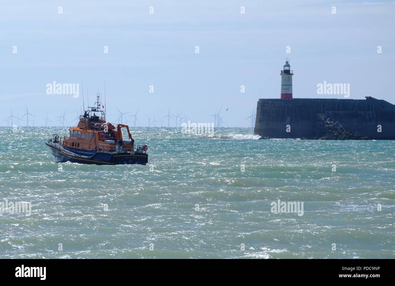 Seaford, East Sussex, UK. 8th August 2018. The RNLI responds to a fishing boat after it got into difficulties in strong winds and washed up on Seaford Beach, East Sussex. Members from Seaford Yacht Club launched an inflatable boat and were first in the scene. A group desperately struggles to save the vessel as it was battered by waves. © Peter Cripps/Alamy Live News Stock Photo