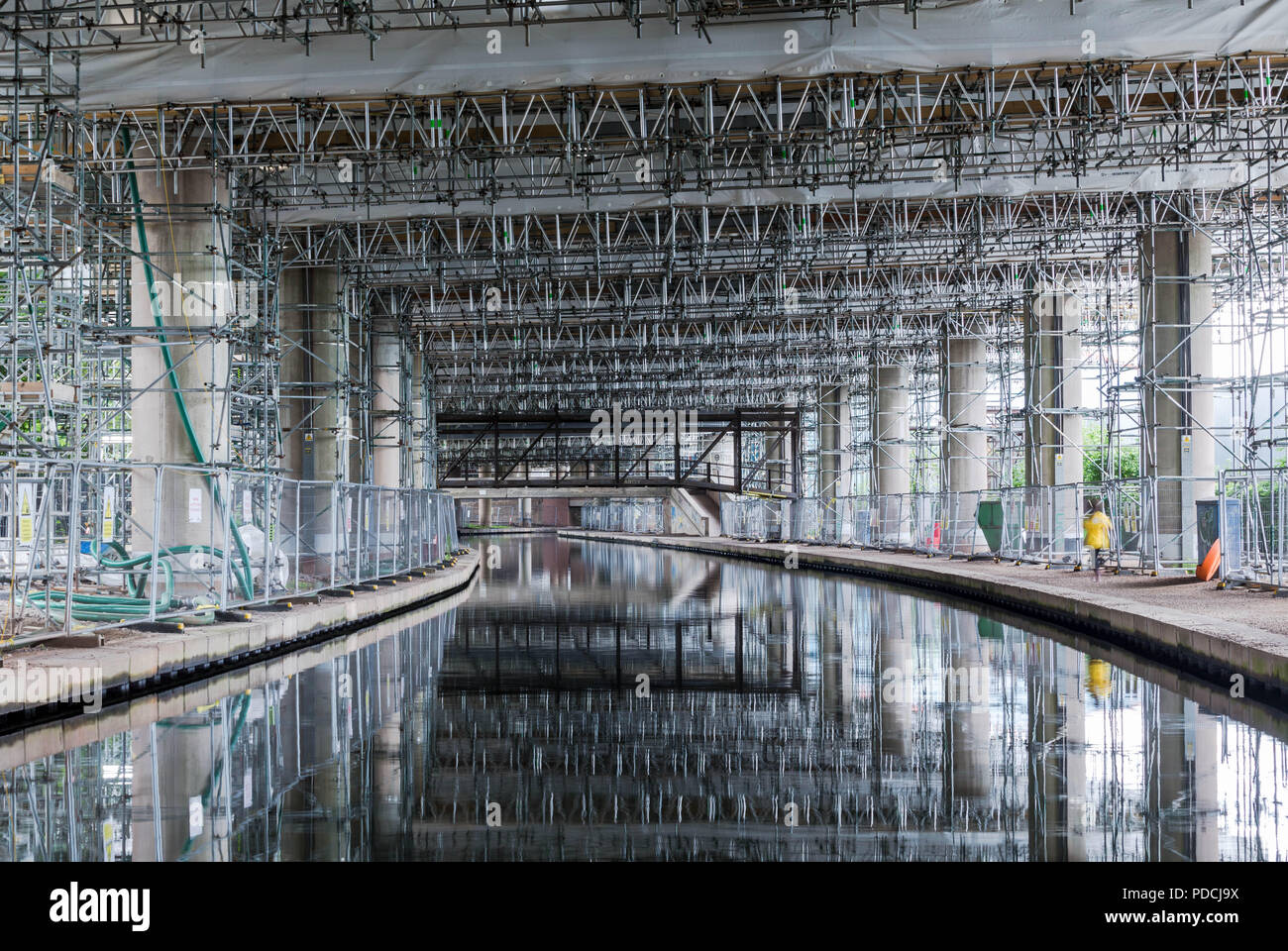 Oldbury, West Midlands, UK. 9th August, 2018. A two-year repair project on the elevated section of the M5 motorway passes its halfway mark. Scaffolding is reflected in the canal. At more than £100 million, M5 Oldbury is believed to be the largest concrete repair project, by value, ever carried out in Britain. Already more than 5,000 separate repairs have been carried out on the southbound carriageway, 3,500 more than anticipated. The Oldbury viaduct carries 120,000 vehicles a day on one of Europe's busiest motorways, and vehicles are limited to 30mph. Peter Lopeman/Alamy Live News Stock Photo
