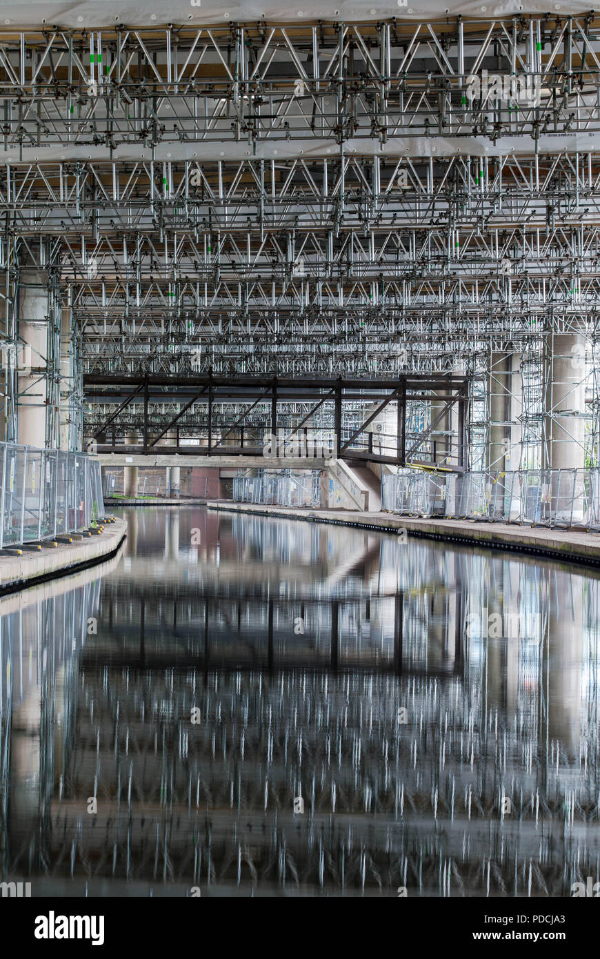 Oldbury, West Midlands, UK. 9th August, 2018. A two-year repair project on the elevated section of the M5 motorway passes its halfway mark. Scaffolding is reflected in the canal. At more than £100 million, M5 Oldbury is believed to be the largest concrete repair project, by value, ever carried out in Britain. Already more than 5,000 separate repairs have been carried out on the southbound carriageway, 3,500 more than anticipated. The Oldbury viaduct carries 120,000 vehicles a day on one of Europe's busiest motorways, and vehicles are limited to 30mph. Peter Lopeman/Alamy Live News Stock Photo
