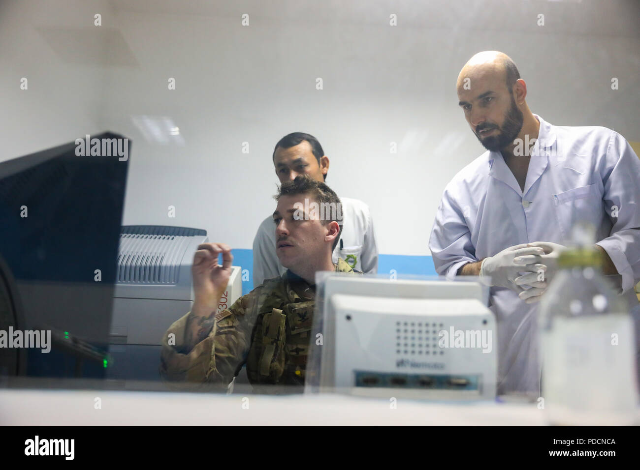 KANDAHAR PROVINCE, Afghanistan (August 5, 2018) -- U.S. Navy Hospital Corpsman 3rd Class Thomas Fite, a radiology technician for Kandahar Airfield NATO Role III Multinational Medical Unit, looks over results of an x-ray, August 5, 2018, to help his Afghan counterparts during a medical advisory visit at Kandahar Regional Military Hospital, Camp Hero in Kandahar, Afghanistan. Staff members from the Role III conduct routine visits to KRMH to train and advice Afghan medical staff. (U.S. Army photo by Staff Sgt. Neysa Canfield/TAAC-South Public Affairs) Stock Photo
