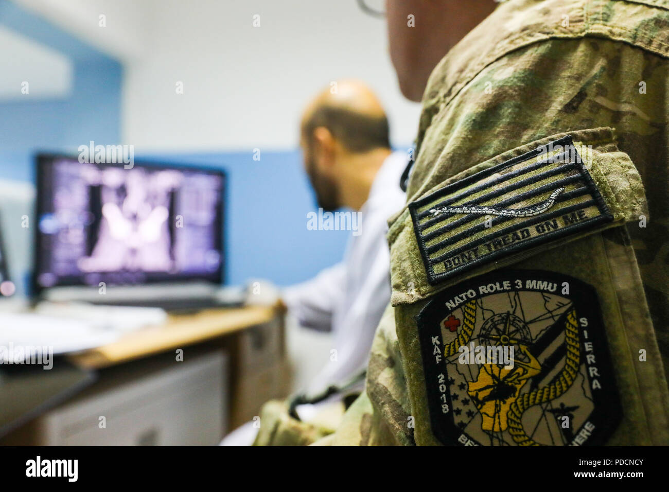 KANDAHAR PROVINCE, Afghanistan (August 5, 2018) -- U.S. Navy Lt. Cdr. Justin S. Clark, radiology technician for Kandahar Airfield NATO Role III Multinational Medical Unit, watches as his Afghan radiology counterpart checks the results of an x-ray, August 5, 2018, during a medical advisory visit at Kandahar Regional Military Hospital, Camp Hero in Kandahar, Afghanistan. Staff members from the Role III conduct routine visits to KRMH to train and advice Afghan medical staff. (U.S. Army photo by Staff Sgt. Neysa Canfield/TAAC-South Public Affairs) Stock Photo