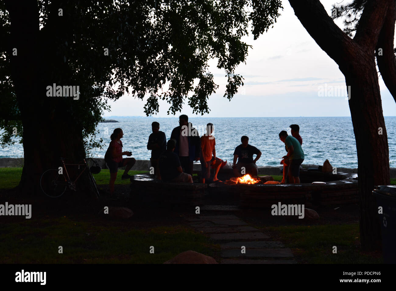 Students From The University Of Chicago Are Silhouetted Against Lake Michigan In The Evening As They Gather Around A Fire Pit On Promontory Point Stock Photo Alamy