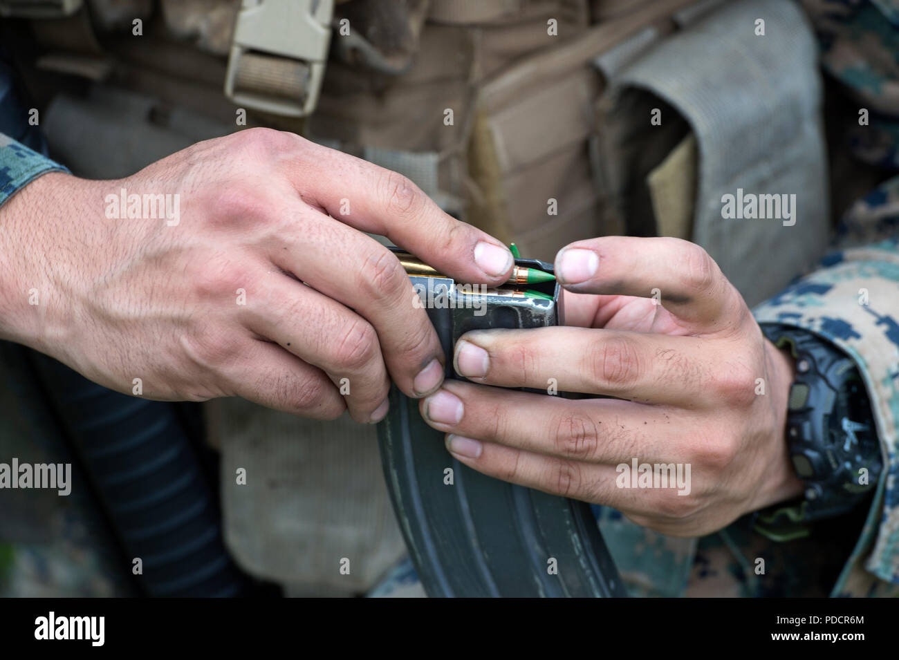 A U.S. Marine assigned to Charlie Company, 1st Battalion, 23rd Marine Regiment loads his M16A4 rifle magazines with 5.56 mm ball ammunition before conducting a live-fire marksmanship event during the 4th Marine Division Super Squad Competition held at Joint Base Elmendorf-Richardson, Alaska, Aug. 6, 2018. During the multi-day competition, squads from 1st and 3rd Battalions, 23rd Marine Regiment and 1st Battalion, 24th Marine Regiment, exercised their technical and tactical proficiencies by competing in events that highlighted offensive/defensive operations, patrolling techniques, combat marksm Stock Photo