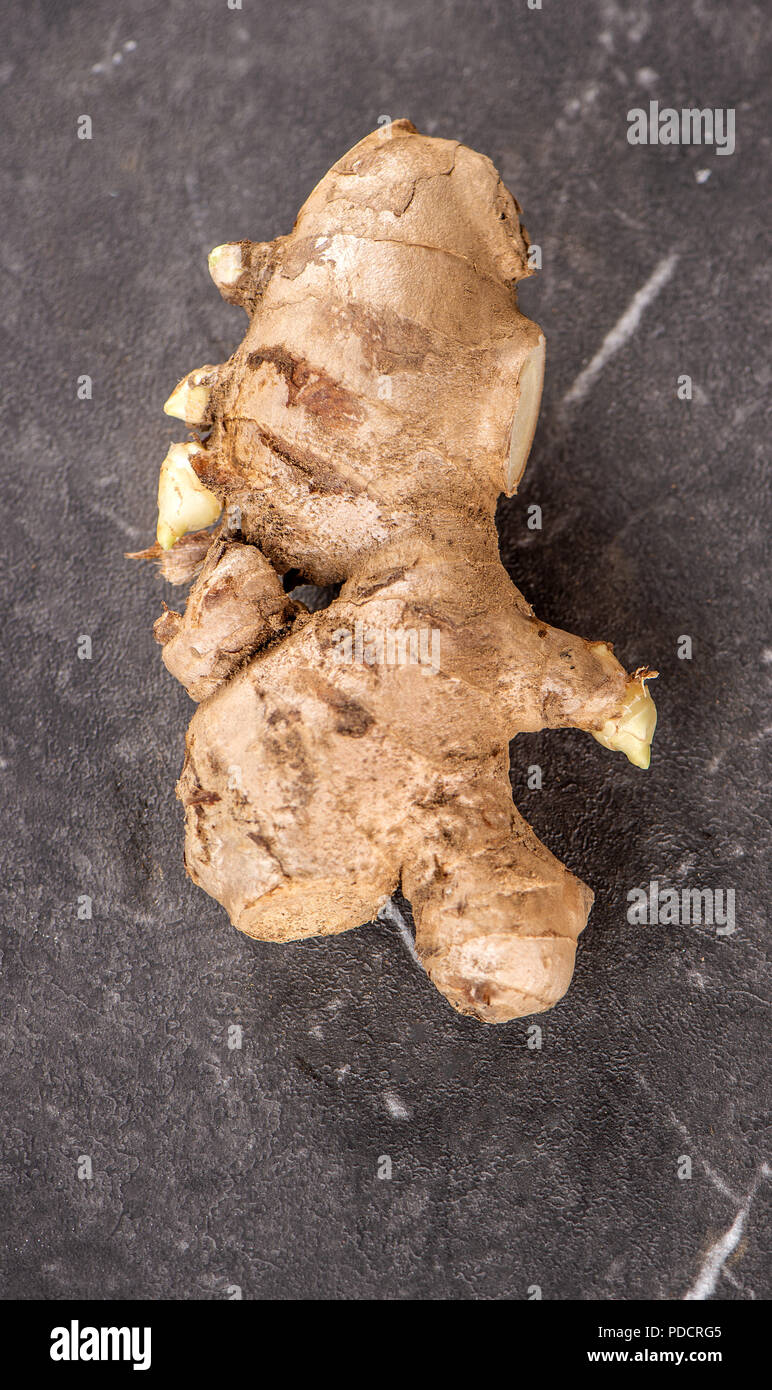 Whole ginger roots on dark old stone background table, space for text. Stock Photo