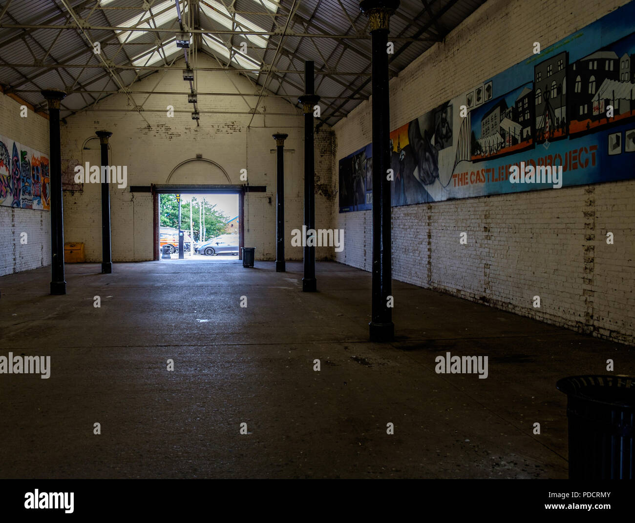 Large empty warehouse with some graffiti on one wall Stock Photo