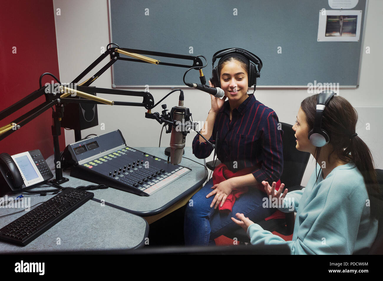 Teenage girl musicians recording music in sound booth Stock Photo