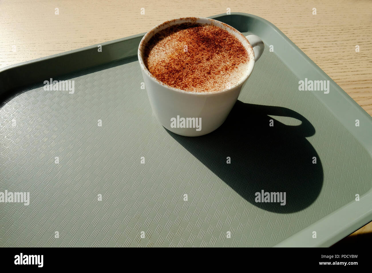 cappuccino coffee in white mug on grey plastic tray Stock Photo