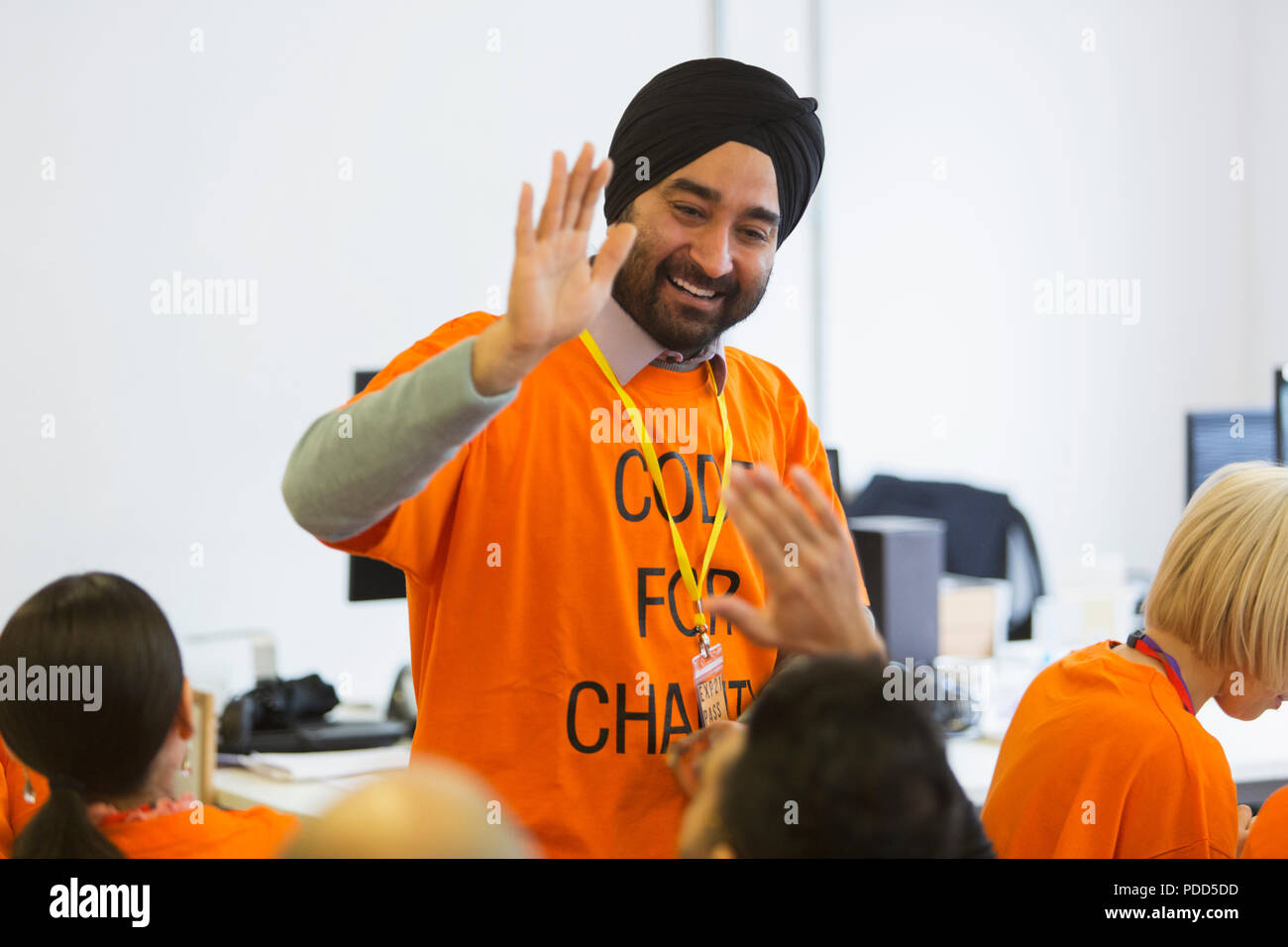 Happy hackers high-fiving, coding for charity at hackathon Stock Photo