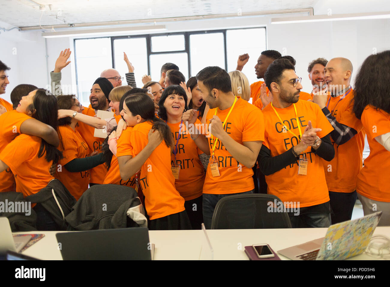 Happy hackers celebrating, coding for charity at hackathon Stock Photo
