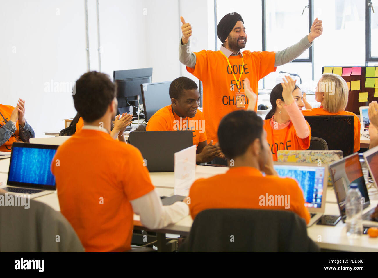 Hackers cheering, coding for charity at hackathon Stock Photo