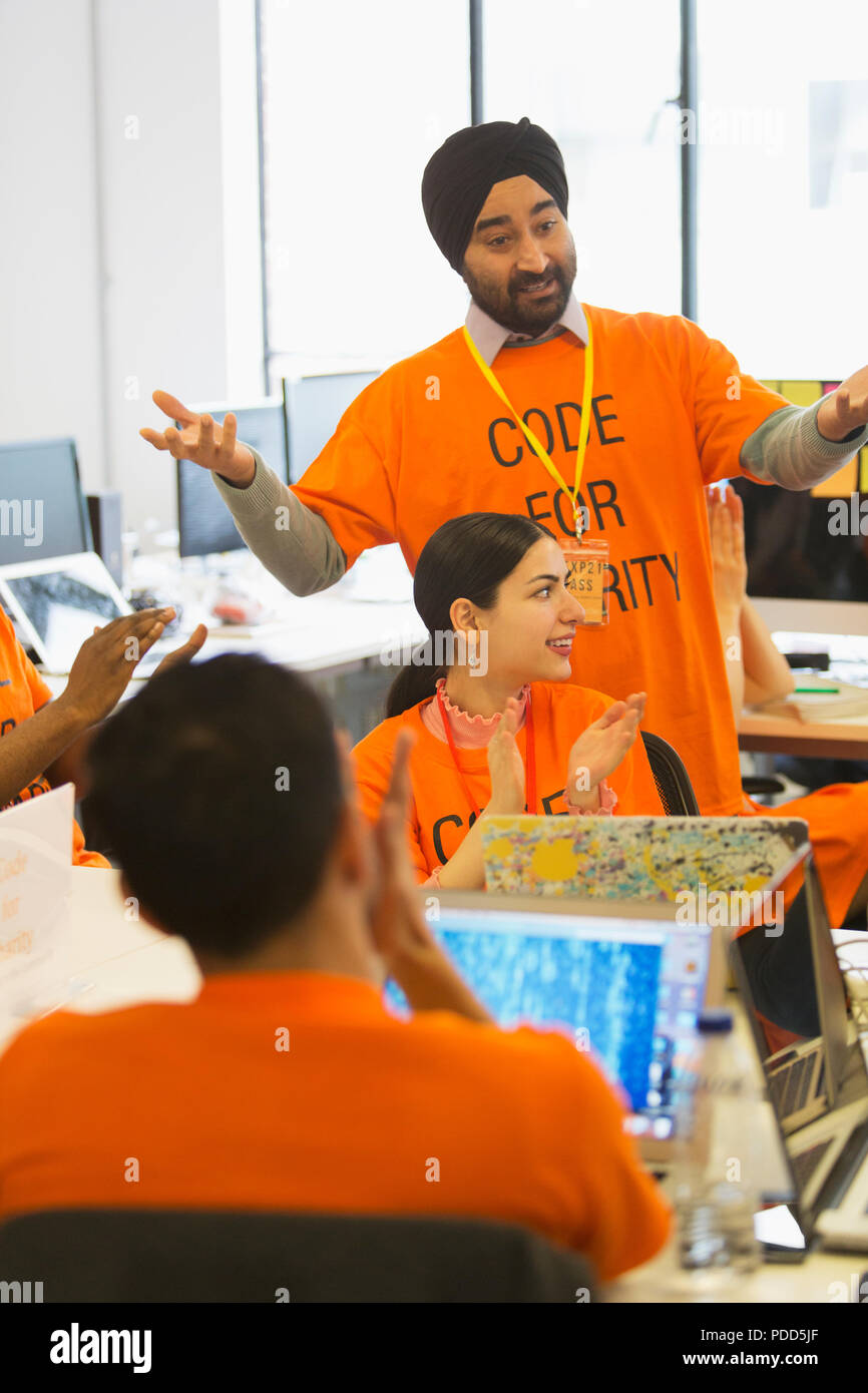 Hackers clapping, coding for charity at hackathon Stock Photo