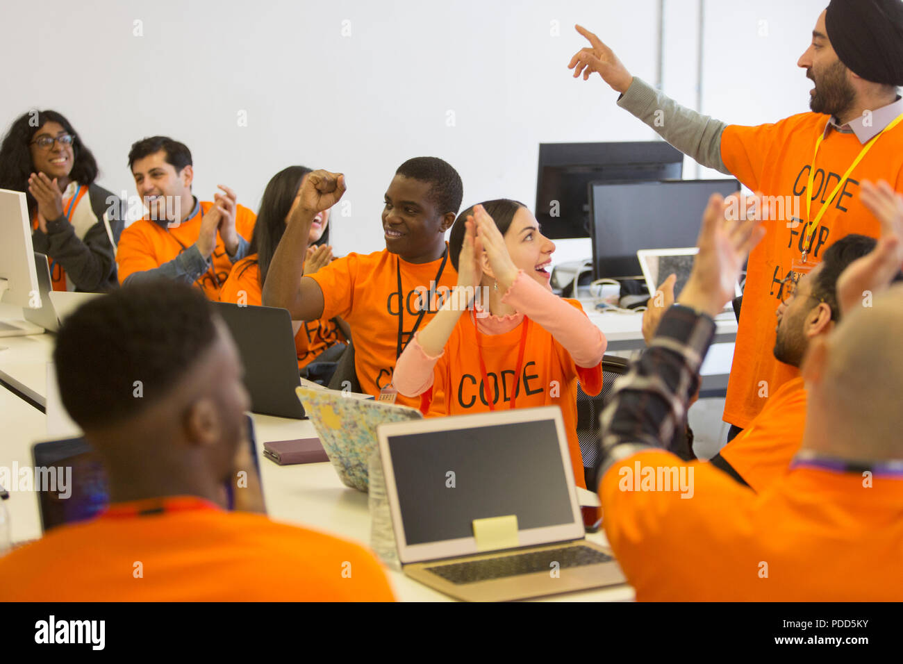 Happy hackers cheering and celebrating, coding for charity at hackathon Stock Photo