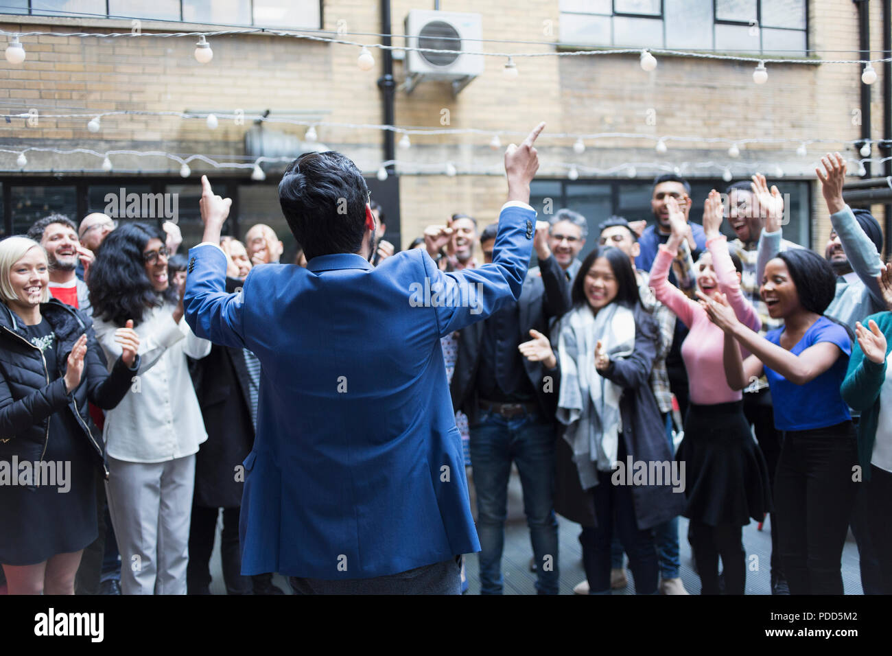 Business people cheering for businessman, celebrating on patio Stock Photo