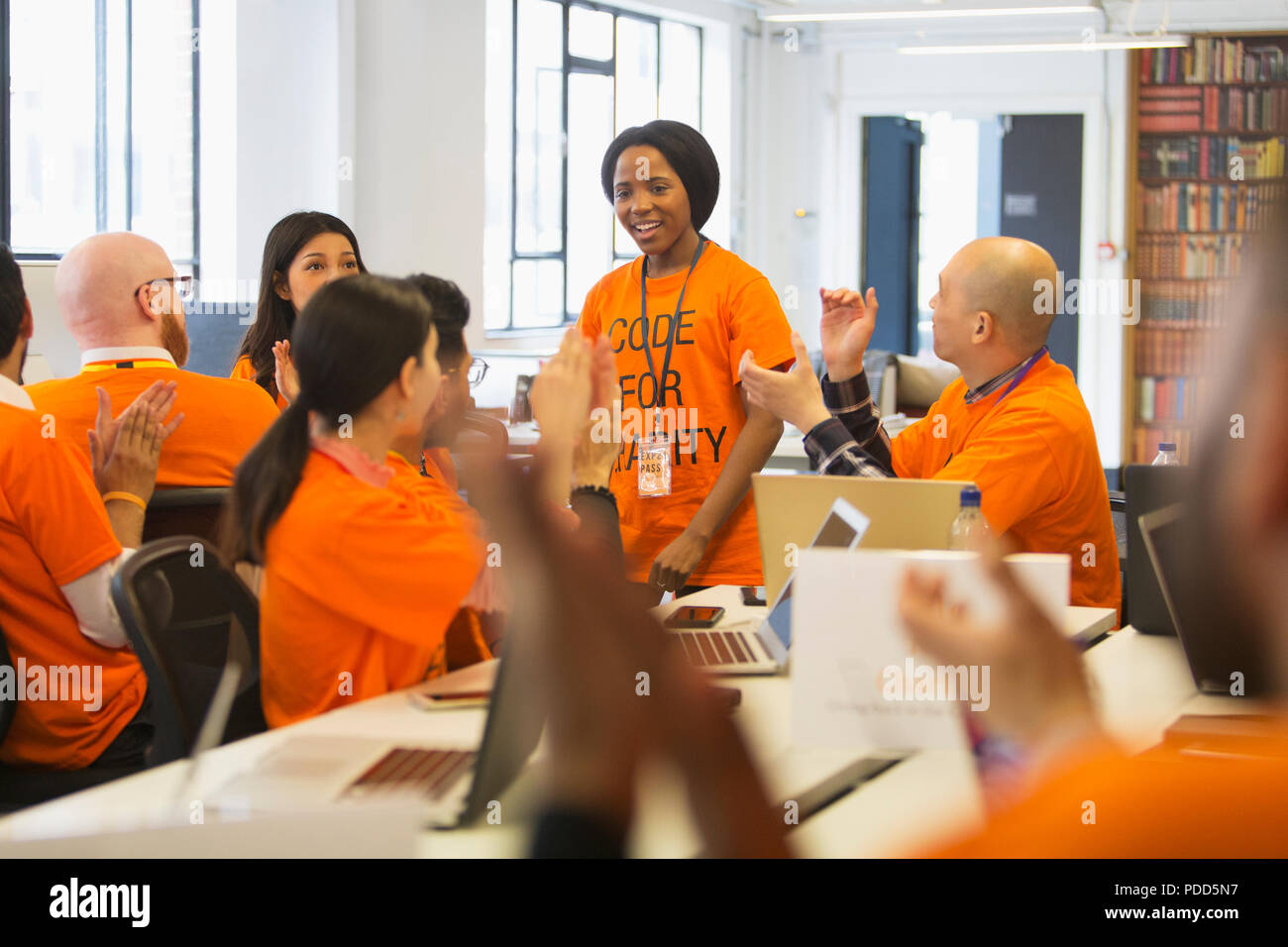 Hackers cheering for woman, coding for charity at hackathon Stock Photo