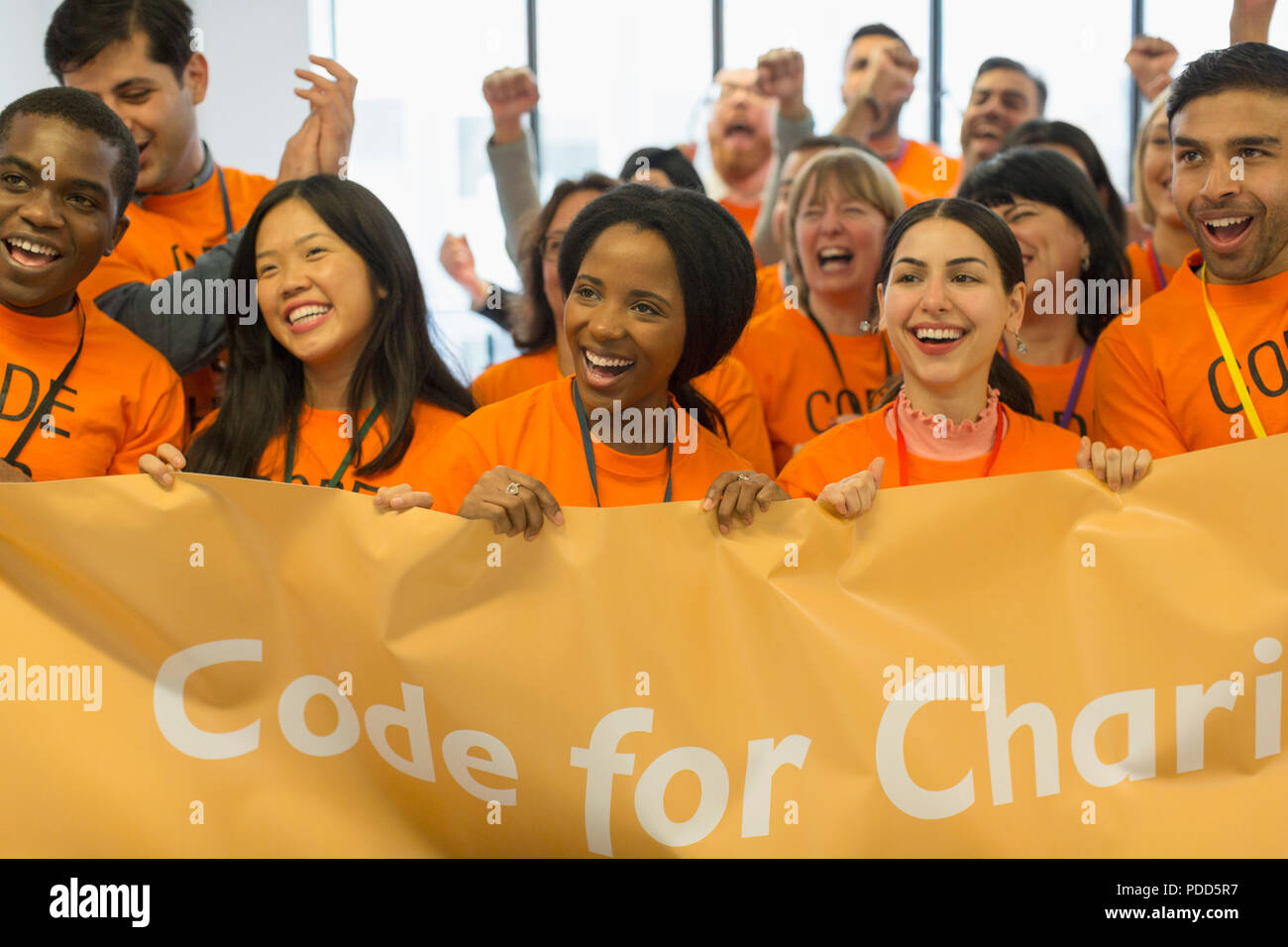 Happy hackers with banner coding for charity at hackathon Stock Photo