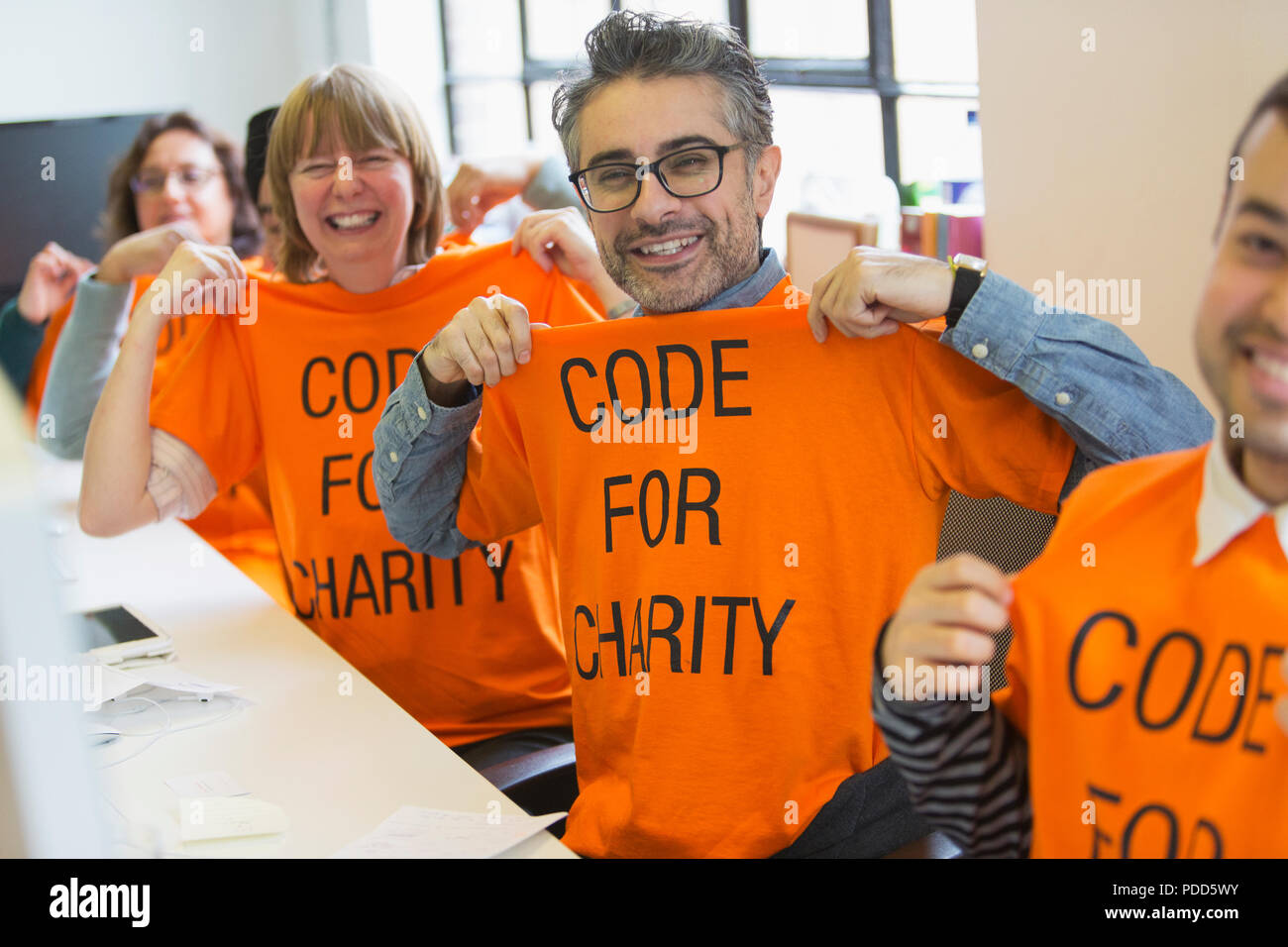 Portrait confident hackers in t-shirts coding for charity at hackathon Stock Photo