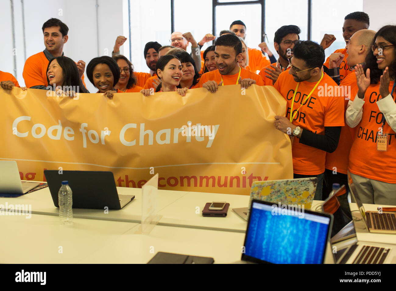 Hackers with banner cheering, coding for charity at hackathon Stock Photo