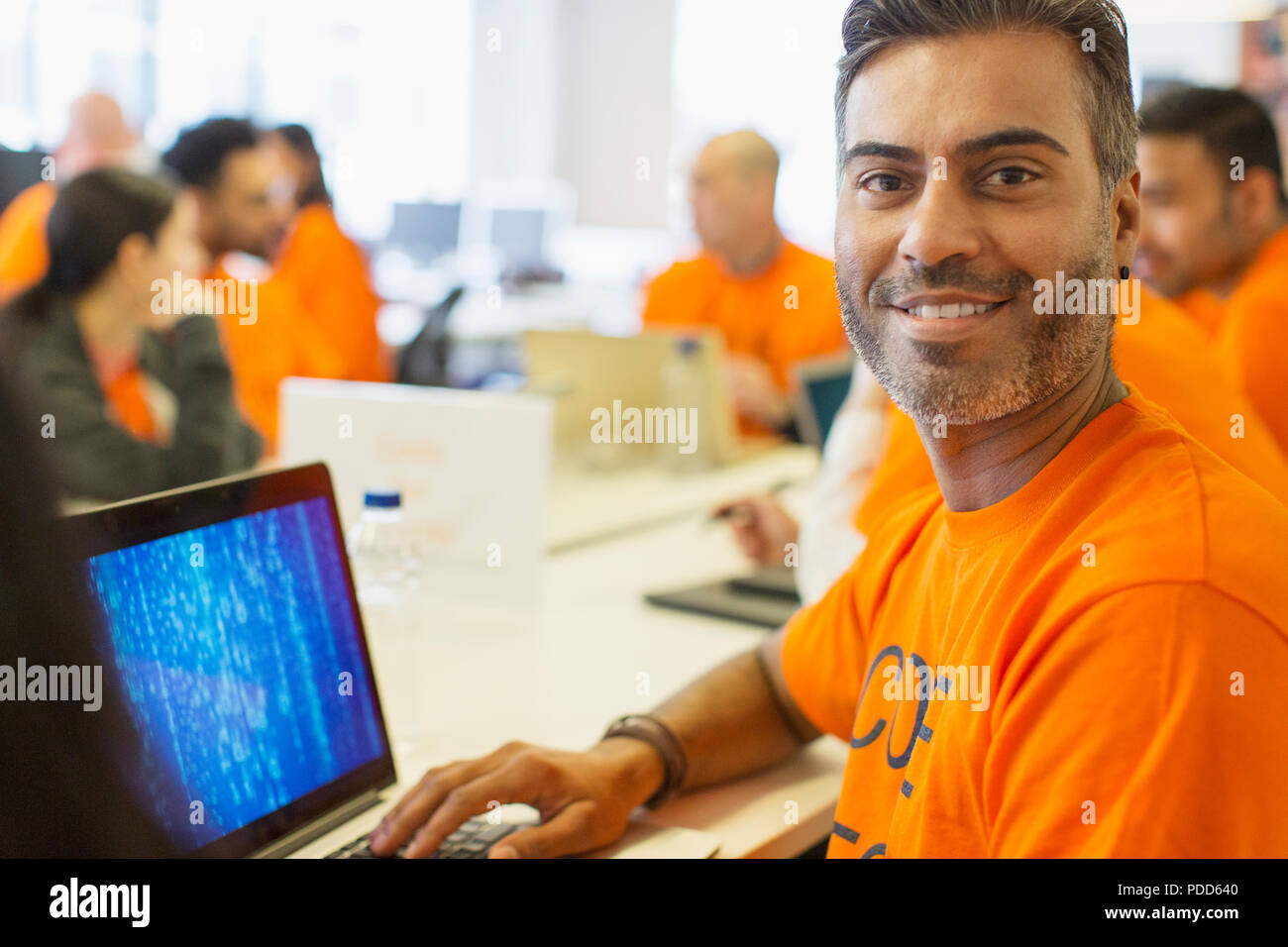 Portrait confident hacker at laptop coding for charity at hackathon Stock Photo