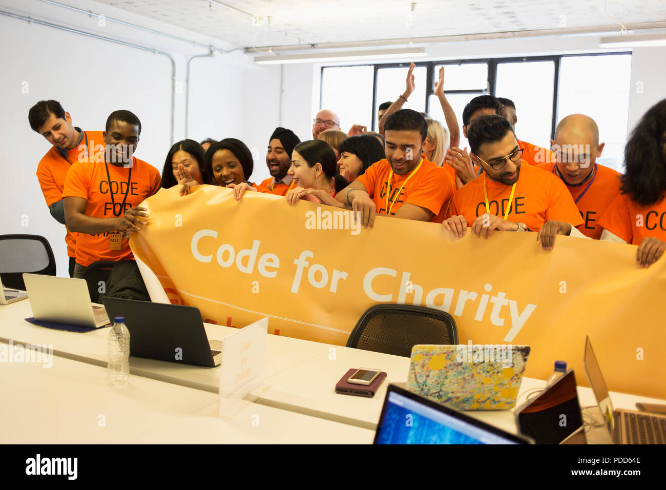 Hackers with banner coding for charity at hackathon Stock Photo