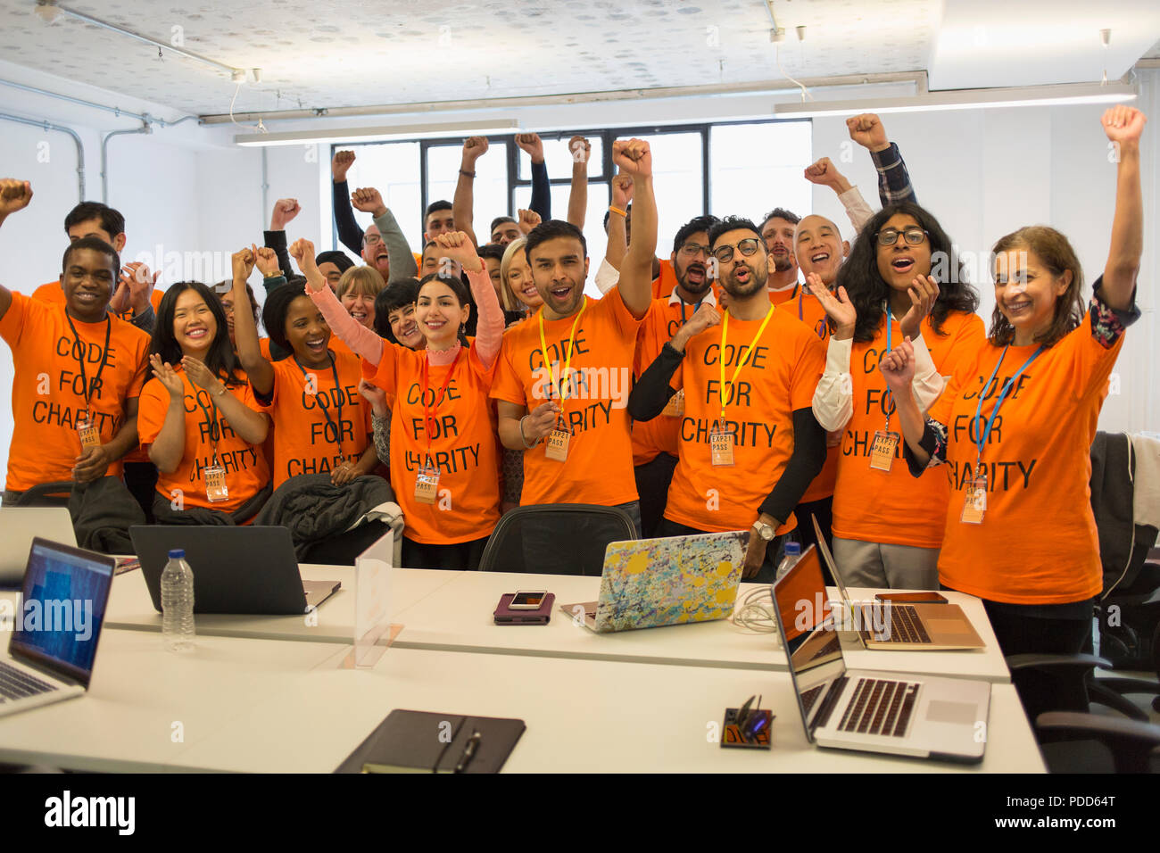 Portrait confident hackers cheering, coding for charity at hackathon Stock Photo
