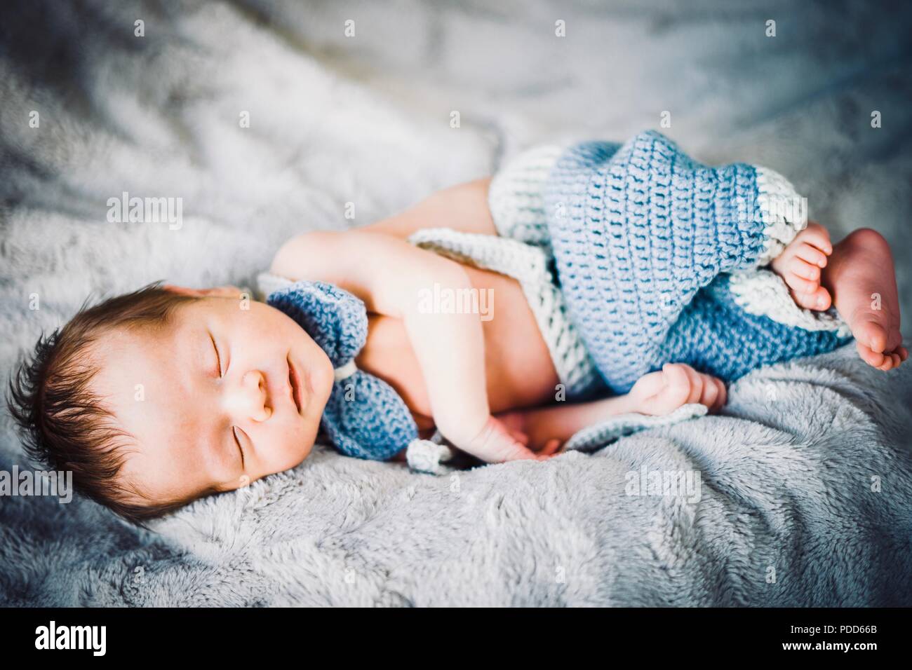 A newborn baby boy sleeping in blue and grey knitted bow tie and