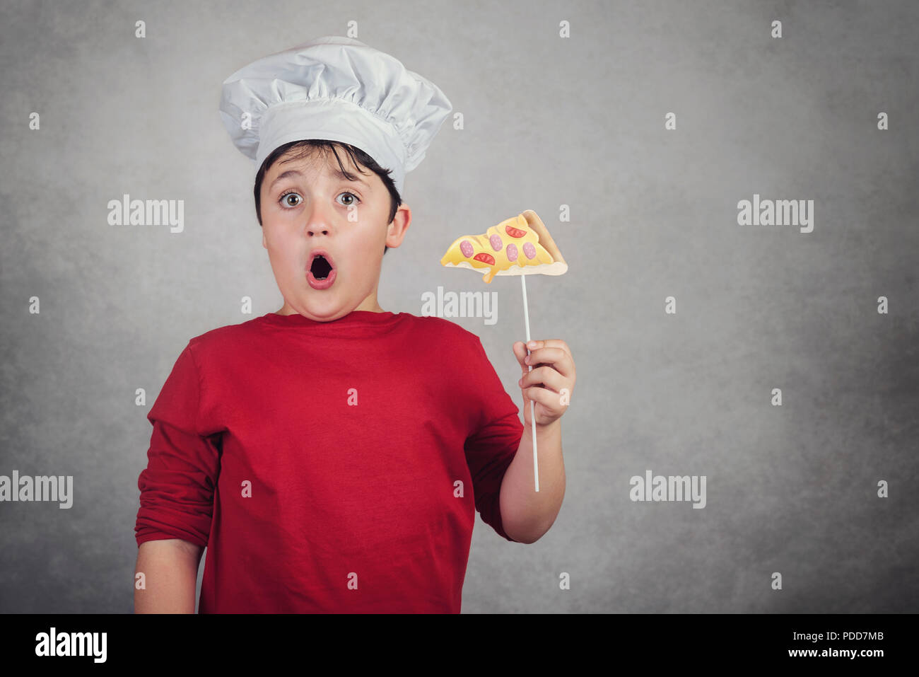 funny child eating a slice of pizza on gray background Stock Photo