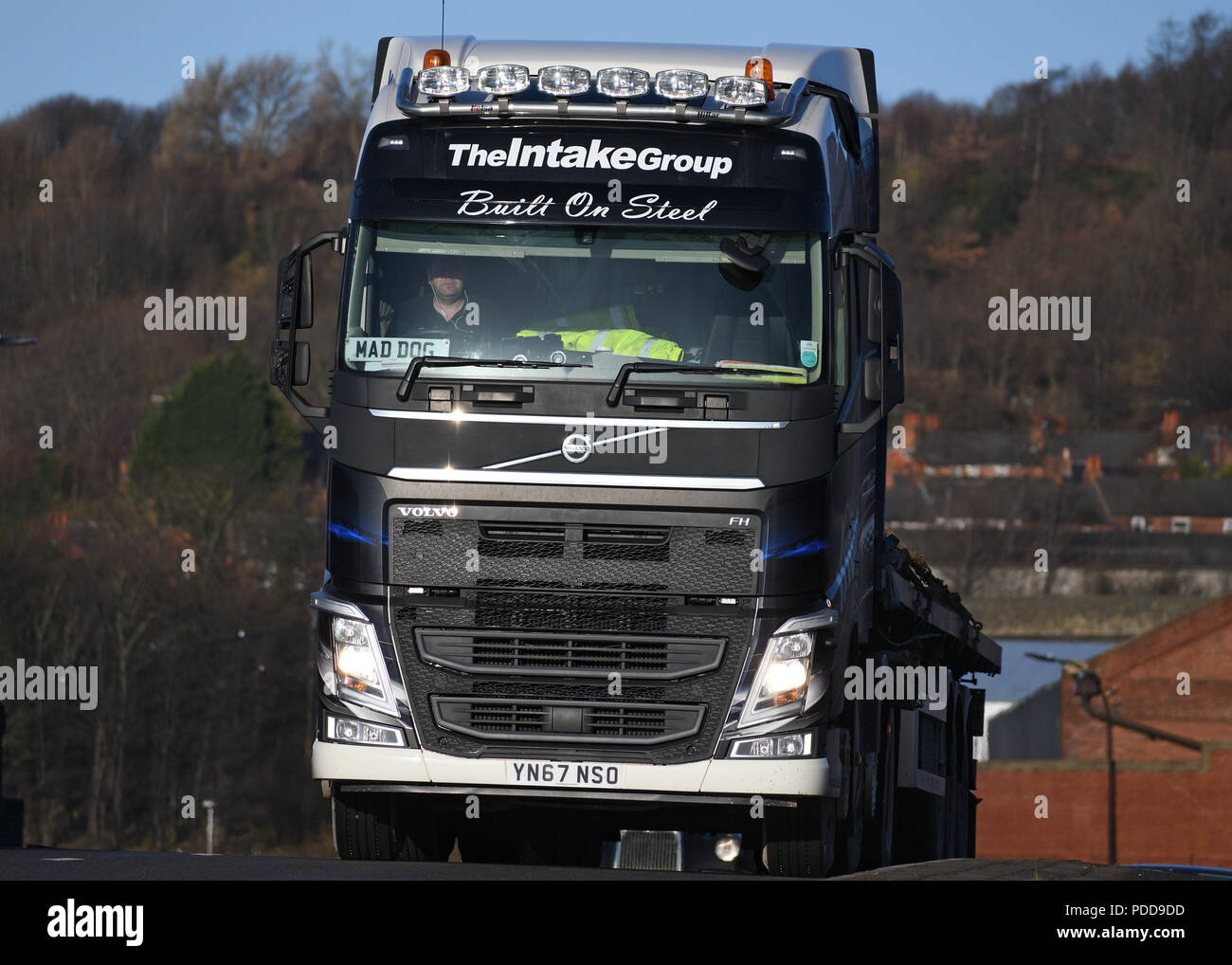Volvo truck pulling flatbed trailer with steel cargo passes Firth Brown steel Works in Sheffield Stock Photo